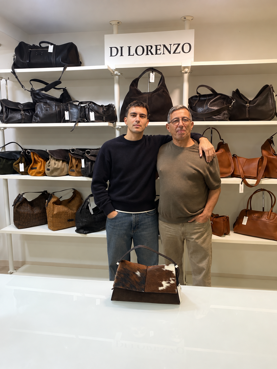 Père et fils dans le showroom DI LORENZO, à côté des sacs de la collection